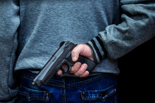 Person holding a handgun behind their back
