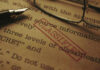 Close-up of a classified document with a pen and glasses