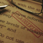 Close-up of a classified document with a pen and glasses