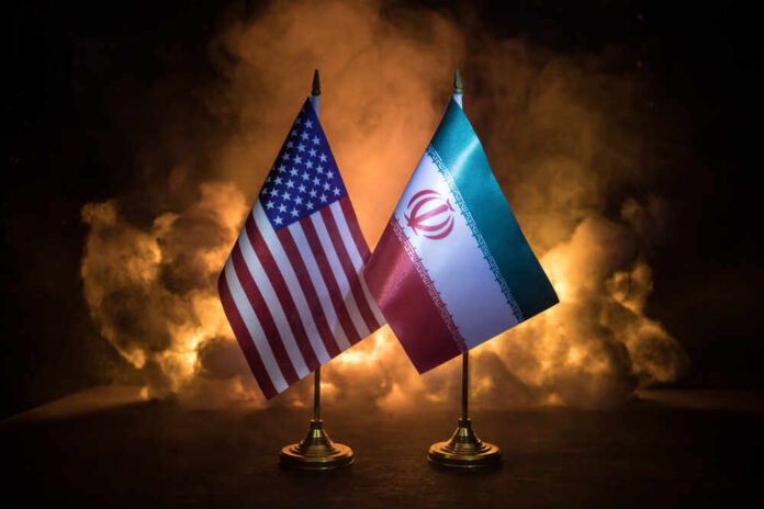 Flags of the United States and Iran displayed on stands with a smoky background