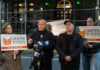 Group of individuals holding signs at a press conference supporting bodega owners