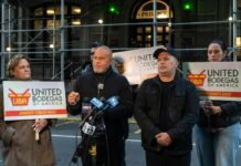 Group of individuals holding signs at a press conference supporting bodega owners