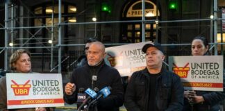 Group of individuals holding signs at a press conference supporting bodega owners