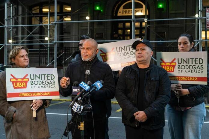 Group of individuals holding signs at a press conference supporting bodega owners