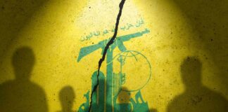 Silhouettes of individuals against a yellow wall featuring Hezbollah's emblem