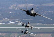 Three military fighter jets flying in formation above a landscape