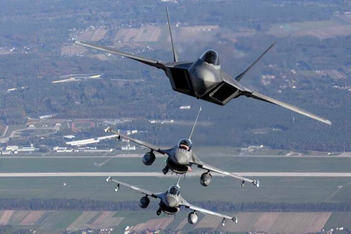 Three military fighter jets flying in formation above a landscape