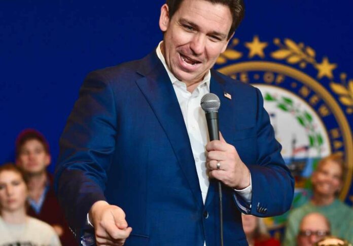 A man in a blue suit speaking into a microphone at a public event