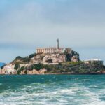 View of Alcatraz Island with buildings and lighthouse surrounded by water
