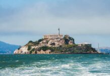 View of Alcatraz Island with buildings and lighthouse surrounded by water
