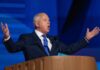 A man in a suit passionately delivering a speech at a podium