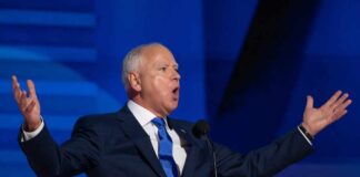 A man in a suit passionately delivering a speech at a podium
