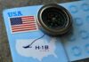 A compass placed on an H-1B visa document with a USA flag