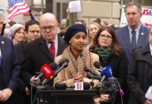 A speaker addressing a crowd at a press conference with microphones in front
