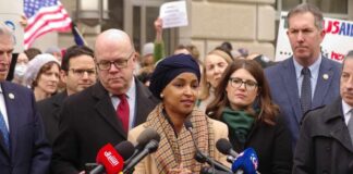 A speaker addressing a crowd at a press conference with microphones in front