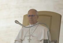 Pope seated on a throne with a microphone in front