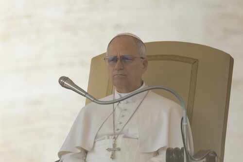 Pope seated on a throne with a microphone in front