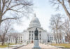 Statue in front of a grand state capitol building on a winter day