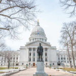 Statue in front of a grand state capitol building on a winter day