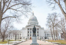 Statue in front of a grand state capitol building on a winter day