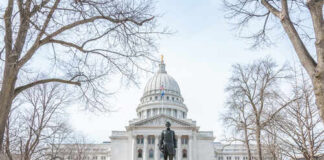 Statue in front of a grand state capitol building on a winter day
