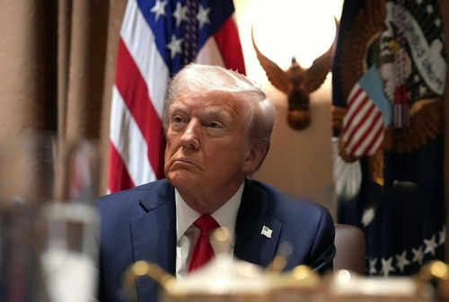 Man in suit sitting with flag background and eagle decoration