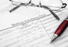 Hospice Enrollment HALTED – Fraud Fears Explode Medicare enrollment form with glasses and pen.