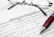 Medicare enrollment form with glasses and pen.