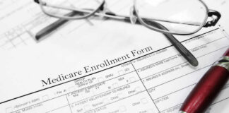 Medicare enrollment form with glasses and pen.