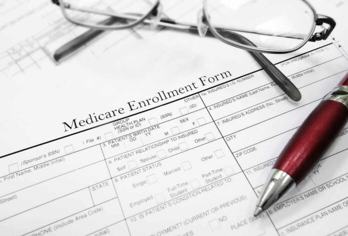 Medicare enrollment form with glasses and pen.
