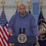 Shock Alarm: Dem Senator Calls Party ‘Anti-American’ Man in a blue hoodie speaking at a podium with U.S. flags behind