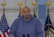 Shock Alarm: Dem Senator Calls Party ‘Anti-American’ Man in a blue hoodie speaking at a podium with U.S. flags behind