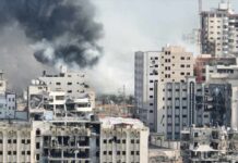 A view of destroyed buildings with smoke rising in the background