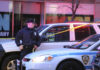 Police officer standing near a crime scene with vehicles and caution tape