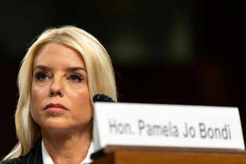 pam-bondi2577942713 Woman sitting behind nameplate at conference or meeting