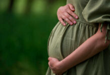 Global Baby Bust Sparks Economic Fears Pregnant person holding their belly in a green dress
