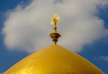 Close-up of a golden dome with a decorative spire against a blue sky