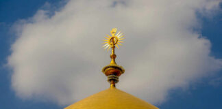 Close-up of a golden dome with a decorative spire against a blue sky
