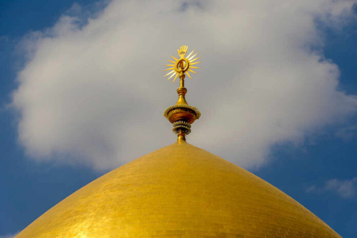 Close-up of a golden dome with a decorative spire against a blue sky