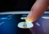 A finger tapping the eBay app icon on a smartphone screen