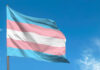 Transgender pride flag waving against a blue sky