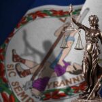 Virginia Court Chaos: Redistricting Battle Continues Bronze statue of Lady Justice in front of the Virginia state flag