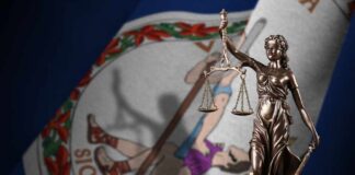 Bronze statue of Lady Justice in front of the Virginia state flag