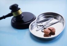 A gavel next to a surgical tray containing medical instruments and an anatomical model