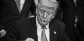 A man in a suit signing a document with a focused expression