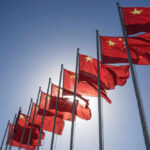 Trump Lands in Beijing—Epic Showdown Begins! Multiple Chinese flags waving against a clear blue sky