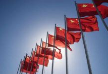 Multiple Chinese flags waving against a clear blue sky