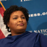 Georgia Senate’s STUNNING Subpoena for Abrams Person speaking at a press conference with flag