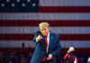 Man points in front of American flag backdrop.