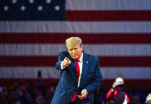 Freedom 250 Meltdown — Who Flipped The Script? Man points in front of American flag backdrop.